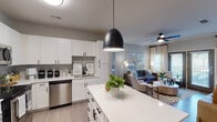 This single-story, 2-bedroom, 2-bathroom residence in Baton Rouge, Louisiana offers a thoughtfully designed open-concept layout with contemporary finishes throughout. The kitchen serves as a central hub, showcasing white shaker cabinetry with matte black hardware, a large island with quartz countertops, stainless steel appliances including a refrigerator, range, microwave, and dishwasher, and pendant lighting overhead. The kitchen flows seamlessly into the living area, which features crown molding, wood-style flooring, a ceiling fan, and French doors that open to an outdoor area, filling the space with natural light.

The primary bedroom is generously sized with multiple windows, a ceiling fan, and carpet flooring, while its en suite bathroom includes a dual-sink vanity with quartz countertops, ample cabinetry, and access to a walk-in closet with built-in shelving. The second bedroom offers flexibility as a home office or guest room, with a large window and ceiling fan. The second bathroom features a tub-shower combination and white vanity. A dedicated laundry area with in-unit washer and dryer hookups adds everyday convenience to this well-rounded residence.