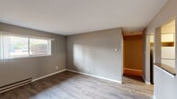 Located at 916 Cypress Point Dr in Crown Point, Indiana, this single-floor unit offers a clean, functional layout with consistent design choices throughout. The living areas feature light-toned vinyl plank flooring that extends seamlessly across multiple rooms, complemented by neutral gray wall tones and crisp white trim and baseboards that create a cohesive, modern aesthetic.

The main living spaces are well-proportioned and filled with natural light courtesy of multiple windows that frame outdoor views of the surrounding neighborhood. Baseboard heating units are present in several rooms, ensuring efficient warmth throughout the colder months, while a wall-mounted air conditioning unit provides cooling comfort in one of the primary rooms.

The kitchen is equipped with white cabinetry featuring wood-trimmed accents, dark granite-style countertops, and white appliances including a range, dishwasher, and refrigerator. Light vinyl flooring ties the kitchen into the overall design of the unit, and ample upper and lower cabinet storage makes it a highly practical space.

The bathroom features a gray vanity with a speckled stone-look countertop, an undermount sink with brushed nickel fixtures, and a lighted mirror above, creating a tidy and well-appointed space. The overall ambiance of the unit is bright, neutral, and move-in ready, offering a straightforward and comfortable living environment.