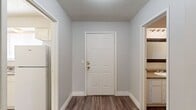 This two-story home offers a practical and well-organized layout, with living space evenly distributed across both floors. The main level features a combined kitchen and living area, where the living room stands out with a wood-burning fireplace framed by a tile hearth and built-in shelving on either side, adding both character and storage. A window allows natural light to fill the room, which is finished with wall-to-wall carpet. The kitchen includes white cabinetry, a built-in pantry with open shelving, and a peninsula countertop, providing ample prep and storage space. A dedicated entry hallway with wood-look flooring connects the main areas seamlessly. The upper floor hosts the three bedrooms, each carpeted and equipped with a ceiling fan and window with blinds, offering comfortable, well-lit spaces. The spacious primary bedroom includes a walk-in closet with dual hanging rods. Three full bathrooms serve the home, each featuring a shower-tub combination. Additional closets provide supplementary storage throughout. Textured ceilings are consistent across the home, and neutral gray walls create a clean, versatile backdrop throughout every room.