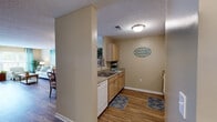 Located at 4211 Fox Rd in Raleigh, NC, this single-floor residence offers a well-organized layout designed for comfortable everyday living. The open-concept living and dining area serves as the heart of the home, featuring durable wood-look flooring, neutral warm-toned walls, and generous natural light streaming through large windows dressed with teal grommet curtains. The living room provides ample space for seating and entertainment, with direct access to an outdoor area via a glass door.

Adjacent to the living space, the dining area comfortably accommodates a round dining table and chairs, flowing seamlessly into the kitchen. The kitchen is equipped with light wood cabinetry, granite-style countertops, white appliances including a coil electric range, over-the-range microwave, dishwasher, and refrigerator, all accented by wood-look flooring.

The bedrooms feature plush carpeting, ceiling fans, and windows that invite natural light. The primary bedroom includes a walk-in closet, while warm accent walls lend a cozy atmosphere to both rooms. The bathroom continues the wood-look flooring theme and is outfitted with a shower-tub combination. Throughout the home, a textured ceiling and consistent neutral palette create a cohesive, welcoming ambiance.