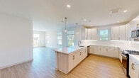 Located at 6461 US-9 N in Howell, NJ, this thoughtfully designed 2-bedroom, 2-bathroom residence offers a bright, modern living experience across a single floor. The open-concept kitchen and living area serves as the heart of the home, featuring light hardwood-style flooring that flows throughout the space. The kitchen is appointed with crisp white cabinetry, a subway tile backsplash, quartz countertops, a central island with a built-in sink, stainless steel appliances including a gas range, microwave, refrigerator, and dishwasher, and stylish globe pendant lighting. Multiple windows flood the space with abundant natural light. The living area extends to a private balcony through sliding glass doors, offering outdoor views of the surrounding area. The primary bedroom is generously sized and includes a dedicated closet. A second bedroom features large windows with natural light. The two bathrooms are finished in a clean, contemporary style — one with a tub and shower combination, and the other with a frameless sliding glass shower enclosure. In-unit stacked laundry adds everyday convenience. The overall ambiance is fresh, airy, and move-in ready.