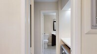 Located at 1845 Summit Pl NW in Washington, DC's vibrant Adams Morgan neighborhood, this one-bedroom, one-bathroom unit offers a well-organized, single-floor layout designed to maximize functionality. The combined living and dining area features light hardwood-style flooring and neutral warm-toned walls, creating a bright and open atmosphere. A large window with vertical blinds fills the space with natural light and provides direct access to a private patio, extending the living area outdoors. The kitchen is equipped with dark espresso-toned cabinetry, white countertops, a stainless steel single-basin sink, and a gas range, offering a practical and stylish cooking space. A dedicated laundry area is conveniently situated adjacent to the bathroom, adding day-to-day practicality. The bathroom features light tile flooring, a dark-framed vanity mirror, a white vessel-style sink set in a dark cabinet, and clean, neutral walls. The bedroom includes light hardwood-style flooring, a narrow window for natural light, and a double closet with bi-fold doors, complemented by a second closet elsewhere in the unit for additional storage. The overall aesthetic throughout the unit is clean and modern with a neutral palette.
