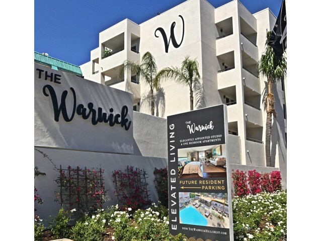 Prominent community signage welcoming residents to studio and one-bedroom apartment homes. - The Warwick