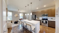 Located in Davenport, FL, this well-appointed 2-bedroom, 2-bathroom residence offers a thoughtfully designed single-story layout with modern finishes throughout. The open-concept living, dining, and kitchen area serves as the heart of the home, anchored by a large central island with a white quartz countertop and bar seating — ideal for casual dining or entertaining. The kitchen is outfitted with stainless steel appliances, warm taupe cabinetry extending to the ceiling, a subway tile backsplash, and recessed and pendant lighting. Wood-look flooring flows through the main living areas, while crown molding and a ceiling fan add polished detail. The living room features a bold accent wall and ample natural light from a window. Both bedrooms are carpeted and tranquil, with the primary offering a generously sized layout and multiple closets. The bathrooms are finished with large-format tile, modern vanities, and a soaking tub. A dedicated in-unit laundry room with full-size washer and dryer adds everyday convenience. With six closets throughout, storage is plentiful in this efficiently designed and stylish Davenport home.