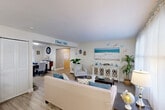 Located at 596 Bullocks Point Ave in East Providence, Rhode Island, this two-story home offers a well-designed layout spread across two floors of comfortable living space. The main floor features an open and inviting living room with light wood-style flooring, large windows that bring in natural light, and a relaxed coastal aesthetic accented by soft blues and neutral tones. The living area flows seamlessly into the dining room, which provides a dedicated space for entertaining. The updated kitchen stands out with crisp white shaker cabinetry, dark granite countertops, stainless steel appliances including a gas range and built-in microwave, and a window that adds natural brightness to the workspace. Upstairs, the two bedrooms offer comfortable retreats, each with ceiling fans, light wood-style flooring, and generous closet space — five closets are distributed throughout the home. The primary bedroom is a well-proportioned space with a ceiling fan and easy access to storage. The second bedroom also features a ceiling fan and a bright window. The full bathroom includes a tub-shower combination with tiled surround. Additional functional spaces include an office, a utility room, and a hallway, completing this well-rounded and move-in-ready home.