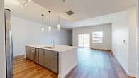 Located in the heart of downtown Phoenix at Roosevelt Row, this modern 2-bedroom, 3-bathroom residence offers a well-designed open-concept floor plan with generous living space spread across a single level. Wood-look flooring flows seamlessly throughout, lending warmth and continuity to every room.

The combined kitchen, dining, and living area serves as the heart of the home. The kitchen is outfitted with white cabinetry extending to the ceiling, stainless steel appliances, and a large island topped with bright white quartz countertops. Stylish pendant lighting hangs above the island, complementing the track lighting above. A pantry and dedicated laundry area add practical convenience. Sliding glass doors in the living room open to a private patio with views of the Phoenix skyline.

The spacious primary bedroom features multiple windows that fill the room with natural light and urban views, and connects to an en-suite bathroom with a wide double-vanity, marble-surround soaking tub, and a separate glass-enclosed marble-tiled shower. A generous walk-in closet with built-in shelving and hanging rods completes the suite. The second bedroom is well-sized with its own access to natural light. Three full bathrooms, three closets, and two hallways round out this thoughtfully laid-out urban residence.