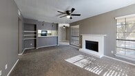 Located at 1598 Weyland Dr in North Richland Hills, TX, this 2-bedroom, 2-bathroom residence offers a thoughtfully arranged single-floor layout with a comfortable and functional design throughout. The open-concept living, dining, and kitchen area serves as the heart of the home, featuring plush carpeting, neutral gray walls, and ceiling fans found throughout the space. The living room is highlighted by a white brick fireplace flanked by large windows that invite an abundance of natural light, creating a warm and inviting atmosphere. Built-in shelving adds a practical accent near the kitchen pass-through. The kitchen is equipped with white cabinetry, light stone countertops, black appliances, and wood-look flooring, offering a clean, contrasting aesthetic. Both bedrooms are generously sized, carpeted, and feature ceiling fans and windows with views to the outdoors. The spacious primary bedroom includes a walk-in closet for ample storage. The bathrooms feature wood-look flooring, white vanities, and clean finishes. Additional highlights include two closets, a dedicated laundry area, and a private balcony. The consistent use of gray tones and white trim throughout lends the space a cohesive, modern feel.