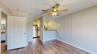 Located at 400 Marion Pugh Dr in College Station, TX, this single-floor unit offers a clean, functional layout with a cohesive design throughout. The living area features warm wood-look laminate flooring, neutral gray walls, and a ceiling fan with a built-in light fixture, lending the space a comfortable, airy feel. A textured ceiling adds a classic touch seen throughout the unit.

The kitchen is thoughtfully appointed with white raised-panel cabinetry, granite-style countertops, and stainless steel appliances including a refrigerator, electric range, and over-the-range microwave. A peninsula counter connects the kitchen to the living area, creating an open flow ideal for everyday living. A pendant light overhead adds a warm accent to this functional space.

The bedrooms are well-proportioned, each with wood-look flooring, neutral-toned walls, ceiling fans, and windows fitted with blinds that allow natural light to filter in. Closet space is accessible from within the rooms, offering practical storage.

The bathroom is neatly finished with white cabinetry for overhead storage, granite-topped vanity, wood-look flooring, and a full tub-shower combination with chrome fixtures. The overall design of the unit prioritizes clean finishes and efficient use of space, making it a practical and comfortable residence.