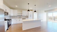 Located at 1109 Horizon Dr SE in New Prague, MN, this well-appointed 2-bedroom, 3-bathroom home offers a thoughtfully designed single-floor layout with modern finishes throughout. The open-concept kitchen and living area serves as the heart of the home, featuring crisp white shaker cabinets, a grey subway tile backsplash, a large center island with quartz countertops, stainless steel appliances — including a gas range, built-in microwave, dishwasher, and French door refrigerator — and stylish matte black pendant lighting. Light wood-look flooring flows throughout the main living spaces, complementing the bright, neutral color palette. The living area is bathed in natural light and opens directly to a private balcony through a sliding glass door, offering outdoor views of the surrounding neighborhood. Both bedrooms are carpeted and generously sized, with the primary bedroom featuring a ceiling fan and large window. Three full bathrooms include clean, white tub-shower and walk-in shower configurations. Additional highlights include three closets, a dedicated laundry area, and a utility room, ensuring practical storage and functionality throughout this contemporary New Prague residence.