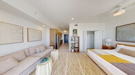 Located at 208 N Federal Hwy in Pompano Beach, FL, this one-bedroom, one-bathroom unit offers a well-designed open-concept layout that maximizes every inch of its compact footprint. The living and sleeping areas flow seamlessly together, bathed in natural light from large sliding glass doors that open onto a private balcony with open city views — a standout feature that brings an airy, coastal ambiance to the entire space.

The kitchen is efficiently designed with warm wood cabinetry, stainless steel appliances including an electric range, over-the-range microwave, and refrigerator, complemented by a clean white countertop and tile flooring. It connects directly to a hallway entry with a sleek, modern front door.

The generous bedroom area features a ceiling fan, a walk-in closet, and access to the balcony, reinforcing the breezy, resort-inspired feel. Neutral tones, recessed lighting, and light tile flooring throughout contribute to a clean, modern aesthetic.

The bathroom is finished with a marble-surround walk-in shower, a wood-vanity with white countertop, and crisp white walls that maintain the unit's bright, contemporary character. Overall, this Pompano Beach residence delivers a cohesive coastal lifestyle experience with modern finishes and thoughtful design.