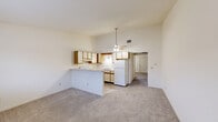 Located at 1017 Daly Dr in New Haven, Indiana, this single-floor, one-bedroom, one-bathroom unit offers a practical and well-organized layout. The open-concept living and kitchen area is the heart of the space, featuring notably tall vaulted ceilings that create a sense of openness well beyond what the footprint might suggest. A ceiling fan with light fixture anchors the shared living-kitchen space. The kitchen is equipped with a peninsula counter that provides additional prep and dining space, cream-toned cabinetry with wood-accented trim, a double-basin sink, electric range, and a full-size refrigerator. Light hardwood-style flooring runs through the kitchen, transitioning to neutral wall-to-wall carpet in the living area and hallway. The hallway connects the main living space to the private areas of the unit. The bedroom is a well-proportioned room featuring textured ceilings, plush carpet, a window allowing natural light, and two separate closets with warm wood-toned doors. The bathroom includes a single-sink vanity with a light stone-patterned countertop, a mirrored medicine cabinet, and a shower-tub combination enclosed by sliding glass doors, complemented by wood-style flooring. The overall palette is light and neutral throughout.