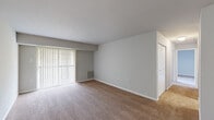 This 2-bedroom, 1-bathroom single-floor unit offers a practical and well-organized layout designed to maximize comfort and usability. The living room is a generously sized, open area featuring warm, neutral-toned carpet and large vertical blind-covered sliding doors that invite natural light and provide outdoor access. A dedicated closet adds convenient storage directly off the living space. The kitchen is neatly appointed with white shaker-style cabinetry, light countertops, and durable wood-look flooring. Black appliances, including a range with overhead ventilation and a full-size refrigerator, complete the functional cooking space. The primary bedroom is a comfortably sized retreat with carpeted flooring, neutral gray walls, and a window fitted with horizontal blinds that allow natural light to filter in. The second bedroom also features carpet and clean, light-toned walls, offering versatility as a guest room or home office. The bathroom is straightforward and well-maintained, featuring a tiled tub-shower combo with chrome fixtures, a white vanity, and wood-look tile flooring. Throughout the unit, a consistent neutral color palette and clean finishes create a cohesive, move-in-ready atmosphere.