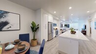 Located at 6717 Calle Koral in Goleta, California, this single-story residence offers a thoughtfully designed open-concept layout with modern finishes throughout. Light wood-tone flooring flows seamlessly across the main living areas, complementing the bright, neutral palette that defines the interior.

The kitchen is a standout feature, showcasing floor-to-ceiling white shaker cabinetry, a quartz waterfall island with an undermount sink, and a full suite of stainless steel appliances including a gas range, built-in microwave, and French door refrigerator. An in-unit stacked washer and dryer is conveniently integrated nearby. The kitchen connects directly to a dedicated dining area, which benefits from natural light through large windows with blinds.

The spacious living room accommodates generous seating arrangements and is outfitted with recessed lighting and a ceiling fan. A secondary living area provides additional flexible space. Bedrooms are well-proportioned, with one featuring plush carpet and ample natural light, while another offers smooth flooring and clean, minimalist design. The bathroom includes a full tub-shower combination, built-in open shelving, and crisp white tile, maintaining the home's cohesive, contemporary aesthetic throughout.