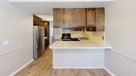 This two-story residence at 900 Long Blvd in Lansing, Michigan offers a thoughtfully designed layout across two floors, providing comfortable living for everyday needs. The main level features hardwood-style flooring throughout the entryway, hallway, and kitchen, creating a cohesive and clean aesthetic. The kitchen is equipped with stainless steel appliances, including a gas range and refrigerator, complemented by rich dark wood cabinetry with ample storage and light countertops. A convenient half bathroom with a wood-cabinet vanity is also located on the main floor. The living and dining areas provide generous room for entertaining and daily living. A classic staircase with white balusters connects the two floors. Upstairs, three carpeted bedrooms offer restful retreats, including a spacious primary bedroom with a built-in vanity nook and a large walk-in closet featuring multi-rod shelving on three walls. Additional bedrooms include sliding-door closets, and crown molding with decorative wainscoting detailing adds charm to some rooms. The full upper-level bathroom features a tub-shower combination with subway tile surround, wood-tone cabinetry, and wood-style flooring. With four closets total and two hallways, storage and circulation are well accommodated throughout this well-maintained home.