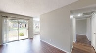 This single-floor residence offers a clean, functional layout designed for comfortable everyday living. The main living area is bright and open, featuring rich dark-toned hardwood-style flooring that extends throughout the unit, neutral gray walls, and a textured ceiling. A full-width sliding glass door floods the space with natural light and provides direct views of a lush green outdoor area, complemented by an adjacent window that further enhances the airy atmosphere. A fireplace adds a classic architectural touch to one end of the living space.

The galley-style kitchen is efficiently arranged with ample upper and lower cabinetry in a light gray finish, light countertops, an undermount sink with a modern faucet, and white appliances including a range, microwave, and refrigerator. A closet at the end of the kitchen offers additional storage.

The bedroom is a well-sized, quiet retreat featuring a ceiling fan with light fixture and generous closet space. The bathroom includes a vanity with a white countertop, illuminated mirror, and built-in shelving above the tub-shower combination. A separate closet area adjacent to the vanity provides convenient wardrobe organization. Throughout the unit, consistent flooring and a cohesive neutral palette create a polished, move-in-ready environment.
