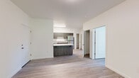 This thoughtfully laid-out 1-bedroom, 1-bathroom unit offers a clean, modern aesthetic across a single floor. Light-toned wood-style flooring runs throughout, lending a cohesive and contemporary feel to every room. The open-concept living area is bright and welcoming, with large windows that frame views of lush greenery and allow natural light to fill the space. A wall-mounted HVAC unit provides individual climate control, and an exterior door offers convenient outdoor access directly from the living room.

The kitchen is a functional standout, featuring dark wood cabinetry that extends to the upper walls, granite-style countertops, and a full suite of stainless steel appliances, including a range, over-the-range microwave, dishwasher, and refrigerator. A peninsula with countertop seating defines the kitchen's edge and creates a natural transition to the living area.

The bedroom is comfortably sized, filled with natural light through large windows overlooking mature trees, and includes a sliding-door closet with built-in shelving. The bathroom completes the unit with a granite-topped vanity with dark cabinetry, a soaking tub with grab bars, and a high clerestory window that introduces additional light while maintaining privacy.