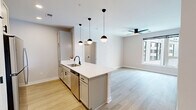 Located at 400 Waterside Drive in Norfolk, Virginia, this well-appointed 2-bedroom, 2-bathroom residence offers a thoughtfully designed single-level layout with modern finishes throughout. The open-concept kitchen and living area serves as the heart of the home, anchored by a large peninsula with a crisp white countertop, under-mount sink, and matte black fixtures. Gray shaker-style cabinetry pairs with stainless steel appliances — including a refrigerator, microwave, and range — while a trio of globe pendant lights adds a contemporary touch overhead. Light wood-look flooring flows throughout the main living area, complemented by a ceiling fan and windows that bring in natural light and views of the surrounding community, including glimpses of a pool. The spacious primary bedroom features plush carpeting and generous proportions, with large windows overlooking the exterior. The second bedroom offers light wood flooring, a ceiling fan, and its own window with community views. Three closets and a dedicated laundry area provide ample storage and convenience. Both bathrooms are finished with wood-look tile flooring, gray vanity cabinetry, white countertops, and matte black hardware accents, with one bath featuring a soaking tub with shower.
