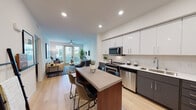 Located at 2200 John Muir Pkwy in Hercules, California, this modern single-floor residence offers a thoughtfully designed open-concept layout with contemporary finishes throughout. Light hardwood flooring flows through the main living areas, creating a cohesive and airy aesthetic.

The kitchen is a standout feature, showcasing a two-tone design with crisp white upper cabinetry and dark charcoal lower cabinets, complemented by a white subway tile backsplash and a full suite of stainless steel appliances, including a range, microwave, dishwasher, and refrigerator. A central island with seating provides an ideal space for casual dining and entertaining.

The open living area is bright and welcoming, with a ceiling fan overhead and large sliding glass doors that invite natural light and provide access to an outdoor area. The space flows seamlessly from kitchen to living room, reinforcing the home's open and connected design.

The primary bedroom features plush carpeting, a bright window with blinds, and generous proportions, while a secondary bedroom offers similarly comfortable accommodations with ample natural light. Both bathrooms are finished with dark charcoal vanities, white quartz countertops, hardwood-style flooring, and large mirrors with integrated lighting, reflecting the home's consistent modern style throughout.