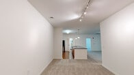 This single-floor residence offers a thoughtfully designed layout comprising two bedrooms, two bathrooms, a kitchen, and a utility room. The open-concept living and dining area is anchored by a centrally positioned kitchen island with a dark granite countertop, pendant lighting, and warm wood cabinetry. The kitchen is equipped with stainless steel appliances, including a refrigerator, range, and microwave, complemented by a tile backsplash and hardwood-style flooring. The living area transitions seamlessly into carpeted spaces, enhanced by a ceiling fan and track lighting overhead.

The primary bedroom is generously sized, featuring plush carpeting, a ceiling fan, and multiple windows that invite natural light and provide views of surrounding greenery. It includes a closet with built-in shelving for organized storage. The second bedroom is similarly carpeted and benefits from a large window with outdoor views.

The two bathrooms are finished with warm tile flooring and wood-toned vanities. One bathroom features a walk-in shower with a glass enclosure, while the second offers a full soaking tub and shower combination with white tile surround and a bright window. The utility room rounds out the functional layout of this well-organized residence.