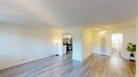 This single-floor unit offers a practical and well-organized layout encompassing a living room, kitchen, one bedroom, and two bathrooms. The living area is bright and open, featuring light-toned laminate wood flooring, a textured ceiling, and large windows with vertical blinds that allow ample natural light to fill the space. A ceiling fan adds functionality, and a wall-mounted air conditioning unit provides climate control. The living area connects openly to the kitchen, which is equipped with white cabinetry, granite-style countertops, a stainless steel gas range, and a built-in range hood. A full-height pantry cabinet and refrigerator complete the kitchen's storage options. The spacious primary bedroom features the same laminate flooring, a wide mirrored sliding closet with built-in shelving, and a large window that brings in natural light. The two bathrooms are clean and functional; one includes a wide vanity with a speckle-finish countertop, a large mirror, brushed nickel fixtures, and a tiled shower/tub combination. Throughout the unit, crisp white walls, consistent flooring, and simple clean-lined finishes create a cohesive, move-in-ready aesthetic.