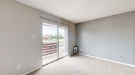 Located at 470 Maxey Rd in Houston, TX, this one-bedroom, one-bathroom unit offers a thoughtfully organized single-floor layout. The living room is finished with soft carpet flooring and neutral gray walls, creating a calm and welcoming atmosphere. Large sliding glass doors open directly onto a private balcony, filling the space with natural light and providing outdoor views of the surrounding greenery. The entryway transitions from wood-look flooring into the carpeted living area, with a coat closet conveniently positioned near the front door. The galley-style kitchen is efficiently designed, featuring gray cabinetry, white appliances including a refrigerator, electric range, and dishwasher, and warm hardwood-style flooring that adds contrast to the bright, clean finishes. The generously sized bedroom is carpeted and includes a ceiling fan, a window for natural light, and direct access to both a walk-in closet and the full bathroom. The bathroom offers a vanity with ample counter space and a full tub-shower combination with clean white tile surround. Two closets throughout the unit provide practical storage solutions. The overall aesthetic is clean, neutral, and functional, making this a well-rounded residential space in east Houston.