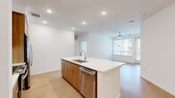 This well-appointed 2-bedroom, 2-bathroom residence in Centennial, CO offers a thoughtfully designed single-level layout with a clean, contemporary aesthetic throughout. Light wood-toned flooring flows seamlessly across the open-concept living areas, complemented by crisp white walls and recessed lighting that create a bright, airy atmosphere.

The kitchen serves as the heart of the home, anchored by a large central island with a white quartz countertop and undermount sink. Warm wood cabinetry extends to the ceiling, providing ample storage, while stainless steel appliances — including a refrigerator, microwave, and dishwasher — complete the modern finish. A subway tile backsplash adds a refined detail to the space.

The living room benefits from generous natural light through large windows fitted with horizontal blinds, and a ceiling fan adds comfort to the space. Both bedrooms are well-sized, with the primary bedroom featuring its own ceiling fan, direct access to a dedicated closet, and an en-suite bathroom. The primary bath is appointed with a double-sink vanity, warm wood cabinetry, large-format tile flooring, and a wide mirror with integrated lighting. The second bathroom mirrors this quality with a single vanity and tiled finishes.

A dedicated laundry room houses a stacked washer and dryer unit with additional shelving, rounding out this functional and modern residence.