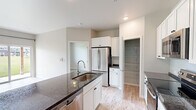 Located at 333 White Cedar Pky in Kimberly, Wisconsin, this one-bedroom, one-bathroom unit offers a thoughtfully designed single-floor layout with modern finishes throughout. The kitchen serves as the centerpiece of the space, showcasing a large island with a deep granite countertop, an undermount sink, and crisp white cabinetry. Stainless steel appliances — including a French door refrigerator, electric range, built-in microwave, and dishwasher — complete the functional and stylish setup. A walk-in pantry provides additional storage just off the kitchen. Light hardwood-style flooring flows throughout the entire unit, lending a clean and cohesive aesthetic. The bedroom is a comfortable size, featuring a large window that overlooks a green outdoor area, bringing in natural light and pleasant views. A dedicated laundry area includes a full-size front-loading washer and dryer with built-in shelving above for added convenience. The bathroom mirrors the kitchen's design language, featuring white cabinetry, dark granite countertops, and a well-placed vanity mirror. The overall ambiance is bright, modern, and move-in ready, making it a practical and attractive living space.