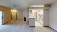This single-floor residence offers a thoughtfully arranged layout that maximizes comfort and functionality. The open-concept living area flows seamlessly into the kitchen, creating an inviting shared space. A tiled fireplace serves as a focal point in the living room, complemented by soft carpeting underfoot and a ceiling fan overhead. The kitchen is well-equipped with white cabinetry, a full suite of appliances including a refrigerator and microwave, a double sink, and a breakfast bar peninsula that separates the kitchen from the living space. Tile flooring in the kitchen provides a clean, durable surface.

The bathroom features a single-sink vanity with ample cabinet storage beneath, a large wall mirror with overhead lighting, and a full tub-shower combination with tiled surround, all set on tile flooring. The bedrooms are carpeted and receive natural light through blinded windows, offering a quiet and comfortable retreat. One bedroom includes an attached en suite bathroom and a ceiling fan light fixture.

Throughout the unit, textured ceilings, neutral warm tones, and consistent wood-trimmed doors and baseboards contribute to a cohesive, clean aesthetic. The entry door is visible from the main living area, providing a straightforward and accessible floor plan.