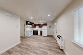 Located at 2351 Westwood Ct in Arcata, CA, this compact and well-designed one-bedroom, one-bathroom unit makes efficient use of its single-floor layout. The open-concept main area seamlessly combines the living room, dining space, and kitchen, creating a functional and cohesive environment. The kitchen is a standout feature, equipped with rich dark-walnut cabinetry, light stone-look countertops, and a full suite of white appliances including a range, microwave, dishwasher, and refrigerator. Recessed lighting illuminates the space throughout, enhancing the clean, neutral palette of the cream-toned walls. Wood-look plank flooring runs consistently through the main living area, adding warmth and visual continuity. A wall-mounted heater near the entry door provides supplemental climate control. The entry door features a transom window above, allowing additional natural light into the space. The bedroom offers a closet and is finished with the same durable wood-look flooring. The bathroom is neatly appointed with matching flooring and clean white fixtures. A door from the main area provides access to an outdoor area with greenery visible beyond, offering a pleasant connection to the surrounding natural setting.