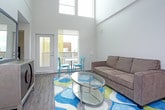 This two-floor residence showcases a contemporary design throughout, combining functional layouts with modern finishes. The kitchen is well-appointed with a full suite of stainless steel appliances, including a refrigerator, electric range, over-the-range microwave, and dishwasher. Rich, dark espresso cabinetry extends from floor to ceiling, providing generous storage, while light-toned countertops offer a clean contrast. Light wood-look flooring runs throughout the kitchen, adding warmth to the space.

The living area is a standout feature, distinguished by dramatically tall ceilings that create an open, airy atmosphere. The generous vertical space lends the room an expansive feel well beyond its footprint.

The bedroom is a calm, comfortable retreat finished with plush carpeting and bright white walls. A walk-in closet provides ample storage and organization space. The room's neutral palette contributes to a serene ambiance.

The bathroom continues the home's modern aesthetic, featuring dark vanity cabinetry with a light countertop, a large mirror, and wood-look vinyl flooring that ties the space together cohesively.

Overall, this residence balances modern design with practical functionality across both levels.
