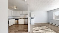 Located at 1527 Seventh Ave in Greeley, Colorado, this 2-bedroom, 1-bathroom single-floor home offers a practical and well-organized layout. The kitchen is a standout feature, outfitted with white cabinetry, granite-style countertops, a white subway tile backsplash, and a full suite of stainless steel appliances including a refrigerator, dishwasher, and range. Wood-look flooring runs through the kitchen and living areas, while an interior stacked washer and dryer unit adds convenient in-unit laundry. The living room is bright and open, benefiting from natural light through window blinds and a wall-mounted air conditioning unit. A hallway connects the main living areas to the two carpeted bedrooms, each featuring baseboard heating, windows with blinds, and a calm, neutral color palette. The primary bedroom includes a mirrored sliding closet, adding a sense of depth to the space. A second closet provides additional storage. The bathroom is clean and straightforward, featuring a full tiled tub-shower combination with chrome fixtures. A pantry rounds out the storage options in this efficiently designed home.