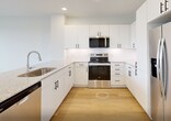 This well-designed 770-square-foot, single-story apartment offers a thoughtful layout with 1 bedroom and 1 bathroom. The open-concept kitchen and living area serves as the heart of the unit, featuring light hardwood flooring throughout. The modern kitchen is equipped with white flat-front cabinetry with matte black hardware, granite countertops, a classic white subway tile backsplash, and a full suite of stainless steel appliances including a refrigerator, range, over-the-range microwave, and dishwasher. A peninsula with a sink adds additional prep and dining space. The living area is bright and airy, illuminated by recessed lighting and a ceiling fan. The living room extends to an exterior door flanked by windows fitted with blinds, allowing abundant natural light. The 160-square-foot primary bedroom features plush carpeting, a ceiling fan, and a window with outdoor views. It connects directly to the full bathroom, which offers a granite-topped vanity with white cabinetry and hardwood flooring, as well as a walk-in closet outfitted with built-in shelving units and dual hanging rods. A hallway and additional closet space complete this clean, contemporary unit.
