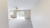 Located at 2512 Magnuson Ct in Bremerton, WA, this well-appointed single-floor unit offers a clean, modern aesthetic throughout. The spacious living area is finished with plush wall-to-wall carpeting and features a ceiling fan with light fixture, providing year-round comfort. A large sliding glass door with vertical blinds floods the space with natural light and opens to views of surrounding greenery. An additional window further enhances the bright, airy atmosphere.

The kitchen is outfitted with crisp white shaker-style cabinetry, granite-look countertops, a stainless steel sink, and black electric range with overhead ventilation — a functional and stylish space for everyday cooking. The wood-look vinyl flooring in the kitchen extends into adjacent areas, creating a cohesive flow.

The bedrooms are carpeted and well-lit, each featuring windows with blinds that frame pleasant outdoor views. Wall-mounted sconce lighting adds a practical touch. The bathroom is clean and efficient, with a full tub-shower combo, white vanity with stone-look countertop, and wood-look vinyl flooring. A dedicated in-unit laundry closet with side-by-side washer and dryer and overhead shelving adds significant convenience. Neutral warm-beige tones and white trim throughout lend a calm, cohesive feel to the entire unit.