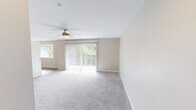 Located at 2512 Magnuson Ct in Bremerton, WA, this well-appointed single-floor unit offers a clean, modern aesthetic throughout. The spacious living area is finished with plush wall-to-wall carpeting and features a ceiling fan with light fixture, providing year-round comfort. A large sliding glass door with vertical blinds floods the space with natural light and opens to views of surrounding greenery. An additional window further enhances the bright, airy atmosphere.

The kitchen is outfitted with crisp white shaker-style cabinetry, granite-look countertops, a stainless steel sink, and black electric range with overhead ventilation — a functional and stylish space for everyday cooking. The wood-look vinyl flooring in the kitchen extends into adjacent areas, creating a cohesive flow.

The bedrooms are carpeted and well-lit, each featuring windows with blinds that frame pleasant outdoor views. Wall-mounted sconce lighting adds a practical touch. The bathroom is clean and efficient, with a full tub-shower combo, white vanity with stone-look countertop, and wood-look vinyl flooring. A dedicated in-unit laundry closet with side-by-side washer and dryer and overhead shelving adds significant convenience. Neutral warm-beige tones and white trim throughout lend a calm, cohesive feel to the entire unit.