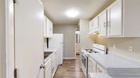 This single-floor residence at 3206 Sunswept Park Dr in Florissant, Missouri offers a functional and straightforward layout designed for comfortable everyday living. The galley-style kitchen is well-equipped, featuring white cabinetry with modern hardware, light speckled countertops, wood-look flooring, a gas range, refrigerator, and dishwasher. A peninsula counter separates the kitchen from the adjacent living area, providing additional prep or dining space. The living area is generously sized, finished with neutral carpet and a sliding glass door that allows natural light to filter in. A textured ceiling is consistent throughout the unit. The bedrooms are carpeted and well-proportioned, each offering ample wall space and natural light from windows with blinds. Closet storage is available in the bedrooms, with louvered bifold doors providing easy access. The bathroom includes a full tub-and-shower combination, a white vanity with a speckled countertop, and wood-look flooring that complements the overall neutral color palette. Soft gray and beige tones are used consistently throughout, creating a cohesive and understated aesthetic across all rooms.
