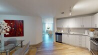 Located at 2160 Van Buren St in Hollywood, Florida, this single-floor residence showcases a contemporary design with a cohesive, modern aesthetic carried throughout every room. Light-toned hardwood flooring runs continuously across the living, dining, and kitchen areas, creating a seamless flow between spaces.

The kitchen is well-appointed with sleek white cabinetry, granite countertops, and a full suite of stainless steel appliances, including a refrigerator, range, built-in microwave, and dishwasher. Track lighting overhead ensures functional illumination. Adjacent to the kitchen, the dining area comfortably accommodates a glass-top table, while an open passage leads into the living room.

The living room is a standout space, featuring a striking textured ceiling that adds visual depth and character. Natural light filters through large windows fitted with horizontal blinds, offering outdoor views of the surrounding area.

The bedrooms continue the hardwood flooring and textured ceiling design, providing a calm and cohesive atmosphere. Two bathrooms serve the unit: one features a spacious glass-enclosed walk-in shower with floor-to-ceiling tile surround and an LED-lit vanity mirror, while the second includes a full soaking tub with a tiled surround. Both bathrooms are finished with granite vanity countertops and neutral tile flooring.
