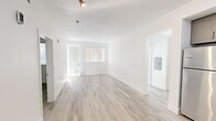 Located on the iconic Sunset Boulevard in the heart of Hollywood, this well-appointed 2-bedroom, 2-bathroom residence offers a clean, modern aesthetic throughout. Light wood-style flooring flows seamlessly across the single-floor layout, complementing the crisp white walls and creating a bright, airy atmosphere.

The open-concept living and kitchen area forms the heart of the home. The kitchen is outfitted with sleek gray shaker cabinets, marble-style quartz countertops, a deep undermount sink, and a full suite of stainless steel appliances, including a refrigerator, range, and over-the-range microwave. The adjacent living room receives abundant natural light and provides direct access to a private balcony.

Both bedrooms are comfortably sized with large windows dressed in vertical blinds that filter in soft, natural light. The primary bedroom offers a generous footprint with ample room for furnishings. A dedicated closet and hallway provide practical storage solutions.

The two bathrooms mirror each other in design, each featuring gray shaker vanities with quartz countertops, tub-shower combinations with white tile surrounds, brushed nickel fixtures, and wood-style flooring. One bathroom includes additional built-in cabinetry for extra storage. The overall design is cohesive, modern, and move-in ready.