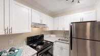 Located at 400 Hawk Ridge Dr in Clemmons, NC, this single-floor residence offers a thoughtfully designed layout that balances functionality and comfort. The kitchen is a standout feature, showcasing crisp white shaker-style cabinetry with brushed nickel hardware, granite-look countertops, and a full suite of stainless steel appliances including a refrigerator and range. Track lighting overhead illuminates the workspace, while a stainless steel sink with a modern faucet adds to the clean aesthetic. Light wood-look flooring runs throughout the kitchen and into the adjoining areas, creating a cohesive, open feel. The living area is comfortably sized, featuring neutral warm-toned walls, a textured ceiling, and a window dressed with blinds and curtains that allow for natural light control. The space flows naturally from the kitchen, making it well-suited for both everyday living and entertaining. The bathroom continues the consistent design language of the residence, with matching granite-look countertops, white cabinetry, a tub-shower combination, and accessibility-friendly grab bars. Throughout the residence, clean lines, neutral tones, and consistent finishes create a cohesive and inviting atmosphere that is both practical and visually appealing.